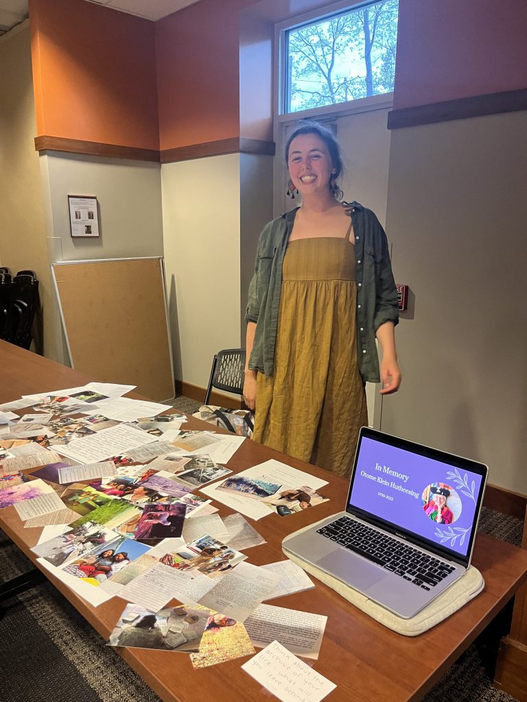 Bella Kirchgessner standing and smiling behind a table with photos, and journal articles